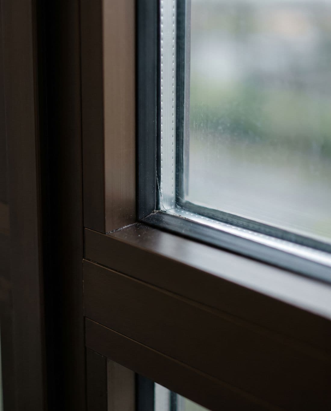 Close study of a window corner: the frame, the glazing bead and the sealed edge of a double-glazed unit where the two panes meet the spacer